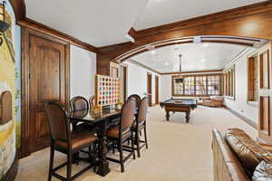 Rec room featuring light carpet, wood walls, crown molding, and billiards