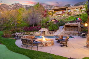 Patio terrace at dusk with a fire pit, a mountain view, and an outdoor pool