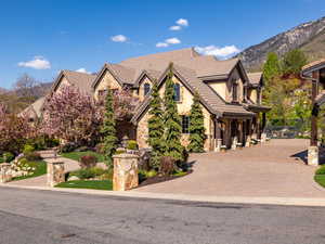 View of front of property featuring stone siding, a mountain view, stucco siding, and a tiled roof