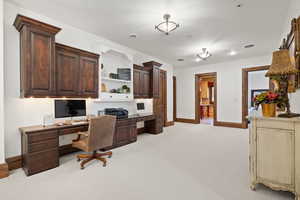 Office featuring built in desk, light carpet, and baseboards