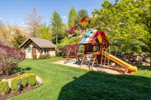 View of playground with a yard and fence