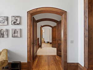 Hall featuring arched walkways and wood finished floors