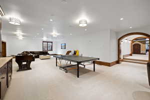 Recreation room with light colored carpet, arched walkways, baseboards, and recessed lighting