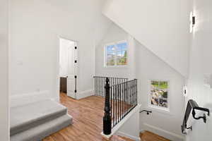 Apartment Stairway with wood finished floors, baseboards, and lofted ceiling