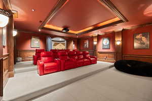 Carpeted home theater room featuring recessed lighting, a tray ceiling, crown molding, and a wainscoted wall