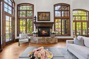 Living room featuring a fireplace, a high ceiling, a healthy amount of sunlight, and wood finished floors