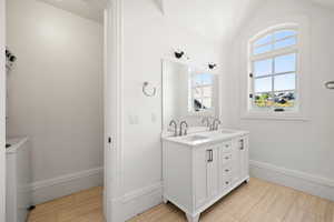 apartment Bathroom with double vanity, vaulted ceiling, baseboards, and a sink