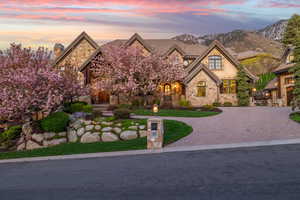French country home with a lawn, a mountain view, stucco siding, stone siding, and curved driveway