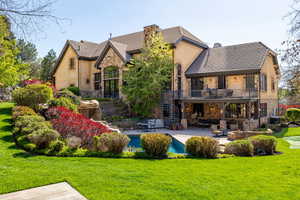Back of property with a balcony, a patio area, stairway, and a lawn