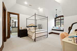 Bedroom featuring lofted ceiling, baseboards, ensuite bathroom, visible vents, and light colored carpet