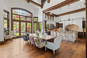 Dining area featuring a high ceiling, beamed ceiling, dark wood-style floors, and french doors