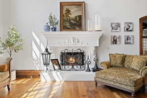 Sitting room with wood finished floors and a warm lit fireplace