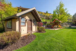 View of side of home featuring a yard, stucco siding, and a playground