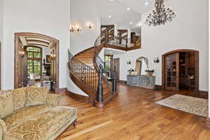 Entryway featuring stairs, hardwood / wood-style flooring, a towering ceiling, a fireplace, and arched walkways