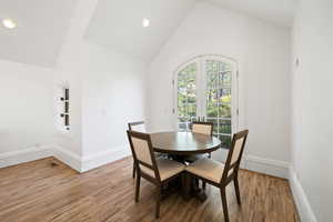 apartment Dining space featuring baseboards, high vaulted ceiling, and wood finished floors