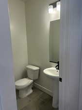 Half bathroom featuring tile patterned floors, toilet, and baseboards