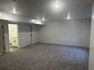 Finished basement with carpet flooring, a textured ceiling, and baseboards