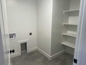 Washroom with hookup for a washing machine, hookup for an electric dryer, dark tile patterned floors, and baseboards