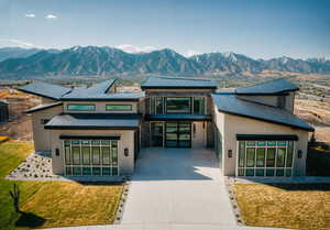 Contemporary house featuring concrete driveway, a mountain view, and stone siding