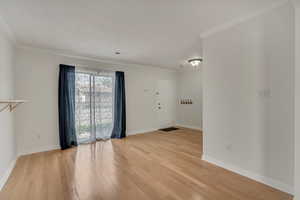Unfurnished room with light wood-style flooring, baseboards, and ornamental molding