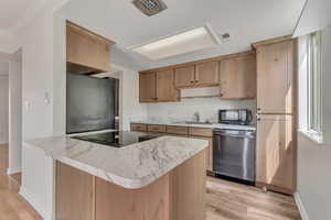 Kitchen featuring black appliances, a sink, light wood-type flooring, and baseboards