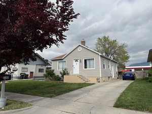 Bungalow-style house with a chimney and a front lawn