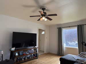 Living room with ceiling fan, light wood-style flooring, and baseboards