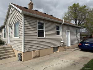 View of property exterior with a chimney, a patio area, and roof with shingles