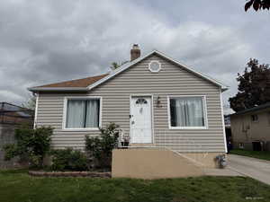 Bungalow-style home with a chimney, central AC unit, and a front yard