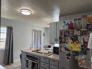 Kitchen featuring appliances with stainless steel finishes, gray cabinetry, light tile patterned floors, light countertops, and a textured ceiling