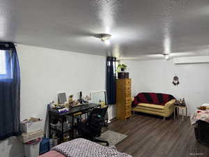 Bedroom with wood finished floors, a textured ceiling, and baseboards
