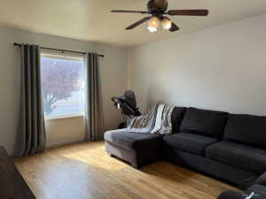 Living area featuring wood finished floors, ceiling fan, and baseboards