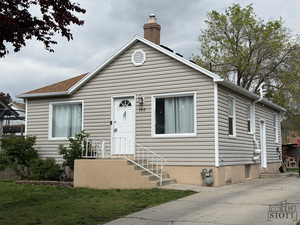 Bungalow-style house with a chimney and a front lawn