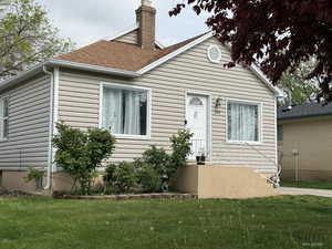 View of front of property featuring a front yard, a chimney, and roof with shingles