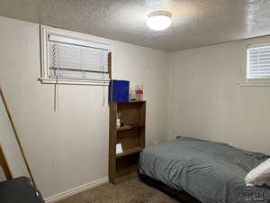 Carpeted bedroom featuring a textured ceiling and baseboards