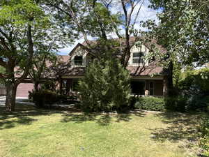 View of property hidden behind natural elements with a front yard