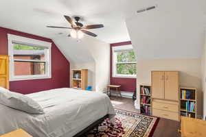 Bedroom with lofted ceiling, synthetic walnut floors, a ceiling fan, and baseboards