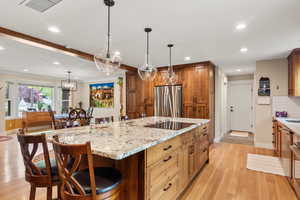 Kitchen with freestanding refrigerator, induction stove top, baseboards, white oak hardwood flooring, and recessed lighting