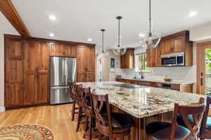 Kitchen with appliances with stainless steel finishes, decorative backsplash, white oak hardwood floors, recessed lighting, and custom built walnut cabinets