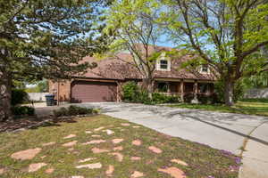 View of front of home featuring covered porch, concrete driveway, a garage, and brick siding