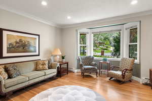 Living area featuring white oak hardwood flooring, recessed lighting, ornamental molding, and baseboards
