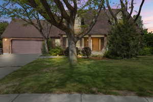 View of front facade with brick siding, concrete driveway, an attached garage, and a lawn