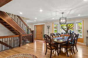 Dining area with a textured ceiling, white oak hardwood flooring, a chandelier, recessed lighting, a stunning custom-built walnut staircase and baseboards