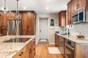 Kitchen featuring appliances with stainless steel finishes, white oak hardwood flooring, custom built walnut cabinetry, and recessed lighting