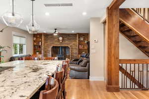 Kitchen featuring ceiling fan, recessed lighting, white oak hardwood flooring, granite counter-tops, and a large island