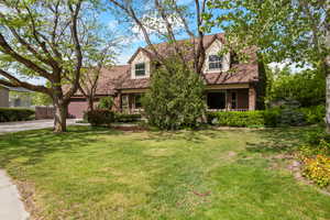 Cape cod house featuring covered porch, driveway, an attached garage, and roof with shingles