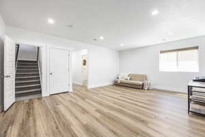 Unfurnished room with light wood-type flooring, recessed lighting, stairway, and baseboards