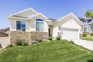 View of front of house with stone siding, stucco siding, driveway, and a front yard