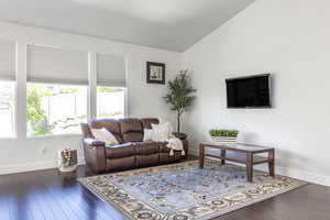 Living room with baseboards, vaulted ceiling, and wood finished floors
