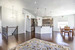 Kitchen with appliances with stainless steel finishes, a kitchen bar, dark wood finished floors, a chandelier, and recessed lighting